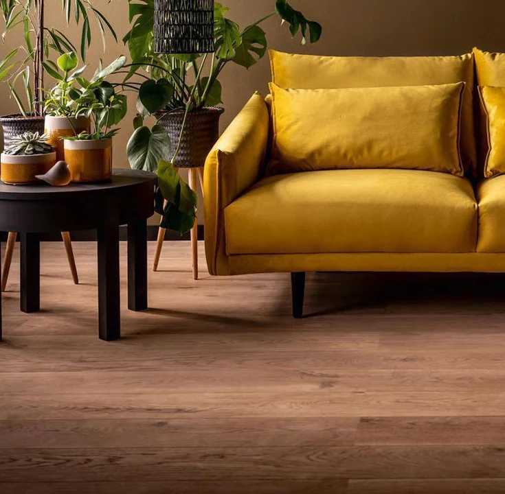 żółta sofa na tle brązowej ściany